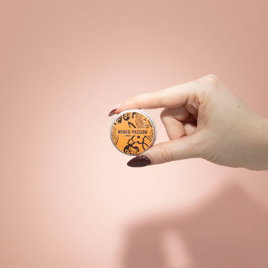 Hand holding a round product labeled 'Mango Passion' against a pink background