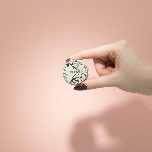 Hand holding a round container with a logo on a pink background