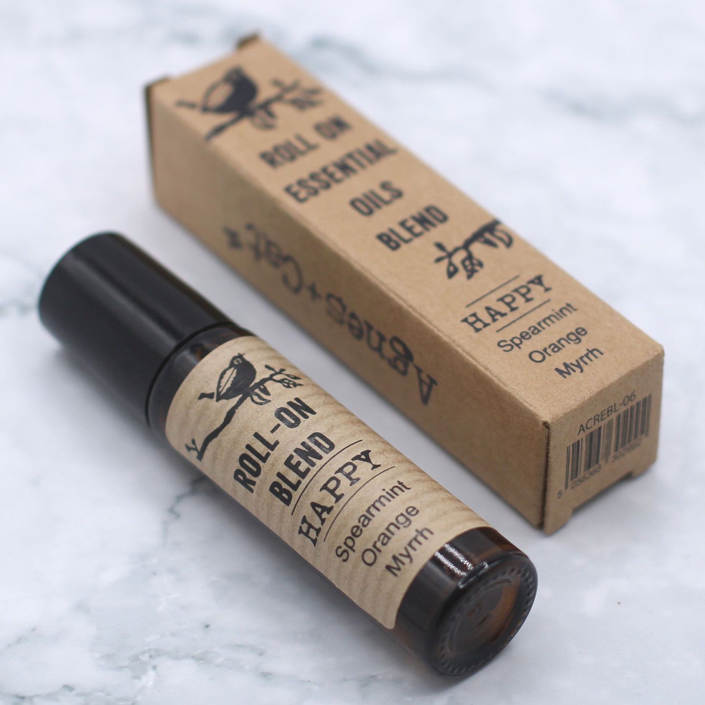 Roll-on blend bottle and box labeled 'Happy' on a marble surface