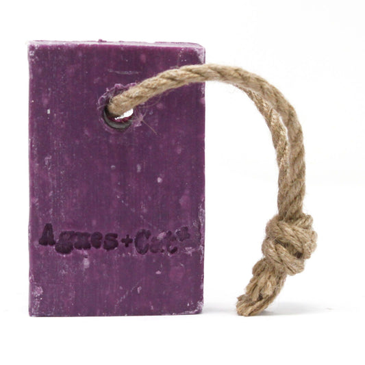 Purple soap bar with a rope on a white background