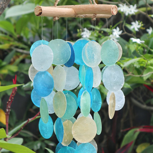 Decorative wind chime with blue and green circular discs hanging against a natural background.