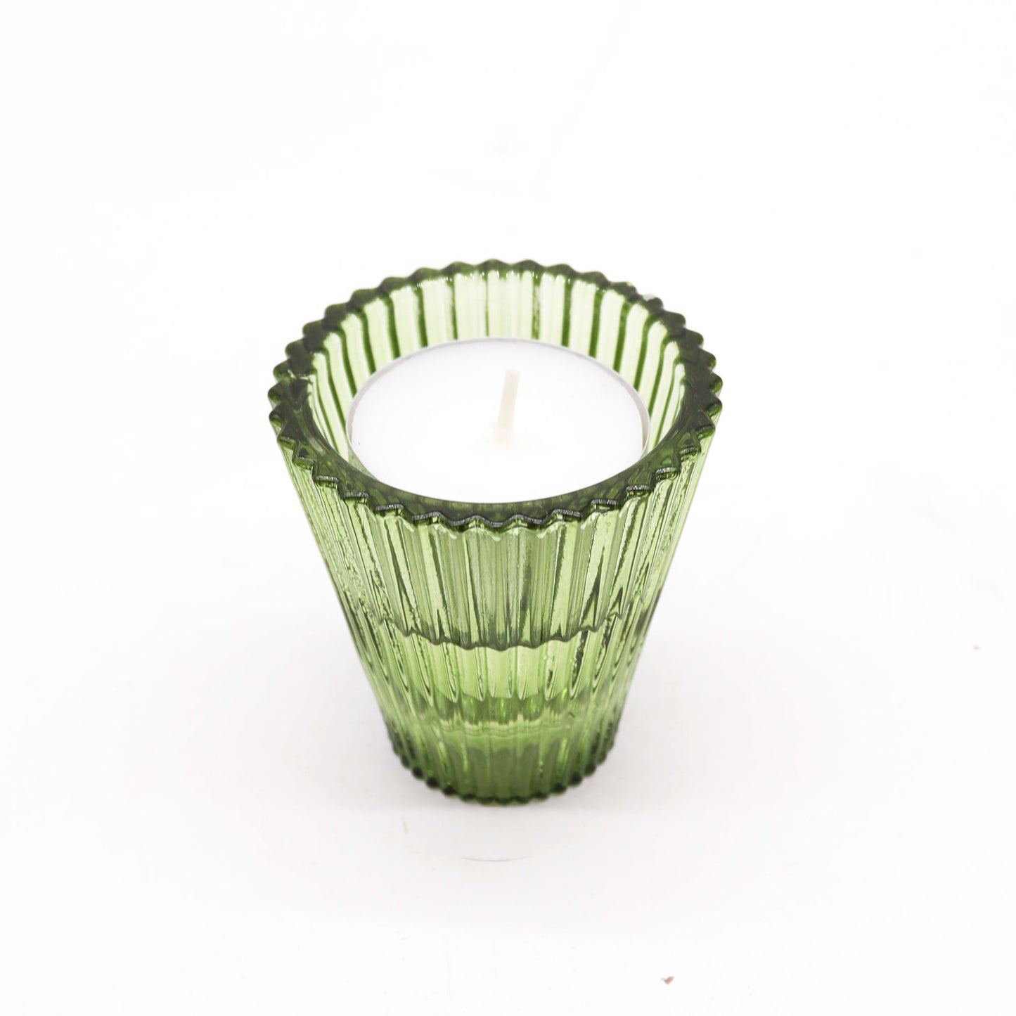 Green ribbed candle holder with a white candle on a white background