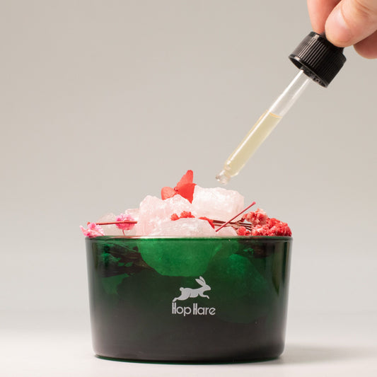 Green container with ice and red flowers, dropper adding liquid, brand 'flop hare' visible