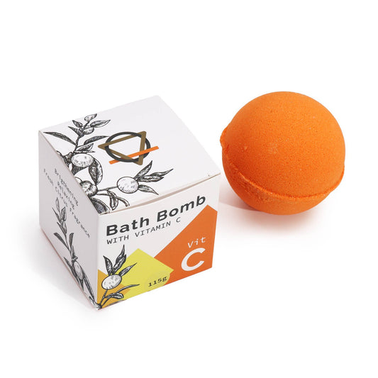 Orange bath bomb next to its packaging on a white background