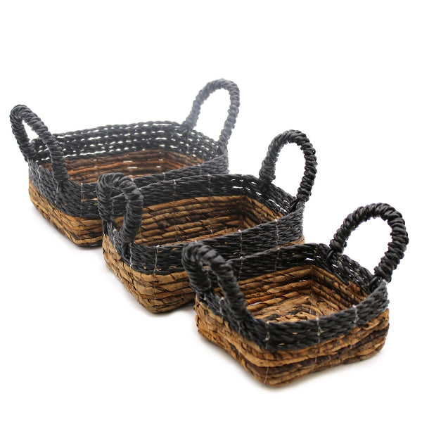 Set of three woven baskets with black handles on a white background
