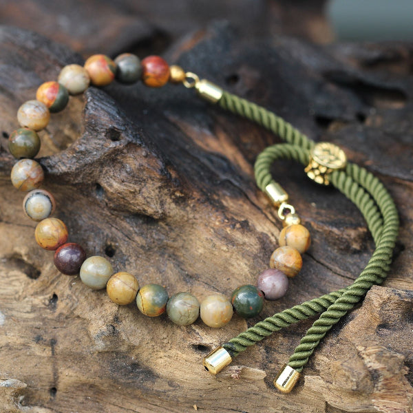 Two bracelets with beaded and braided designs on a wooden surface