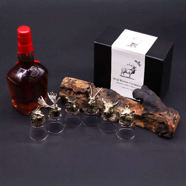 Bottle of whiskey with decorative animal figurines and a box on a dark background