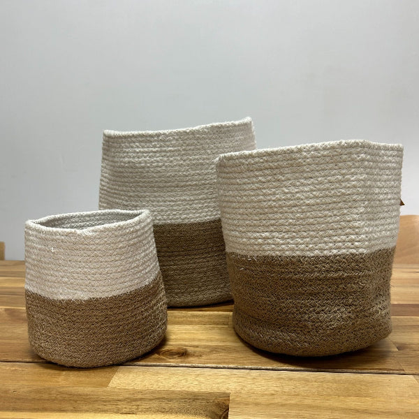 Three woven baskets with two-tone design on a wooden surface