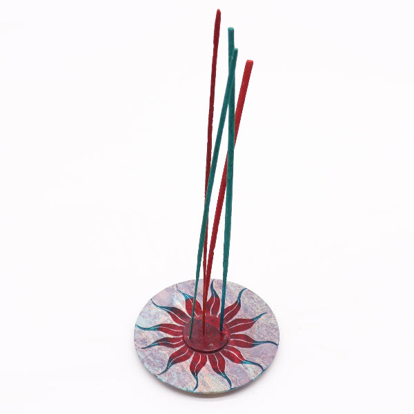 Incense sticks in a decorative holder with a colorful base on a white background