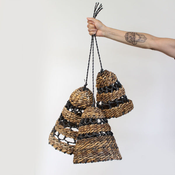 Hand holding a woven basket with black accents against a white background