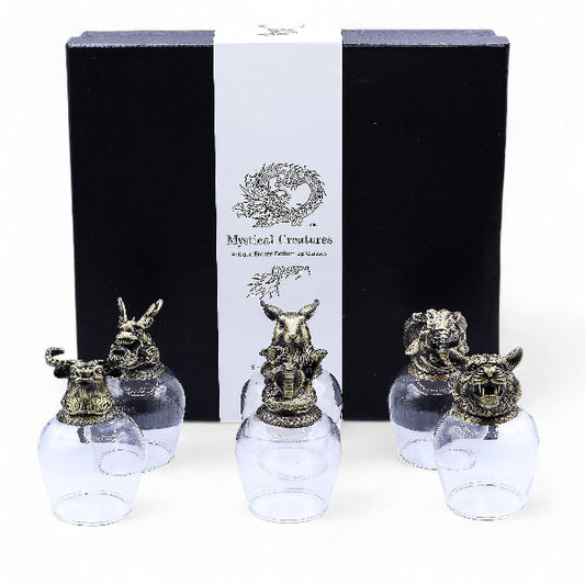 Set of glass bottles with animal head stoppers in front of a 'Mystical Creatures' branded box.