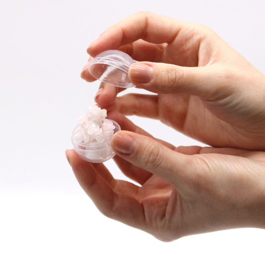 Hand holding a small transparent container with white beads on a white background