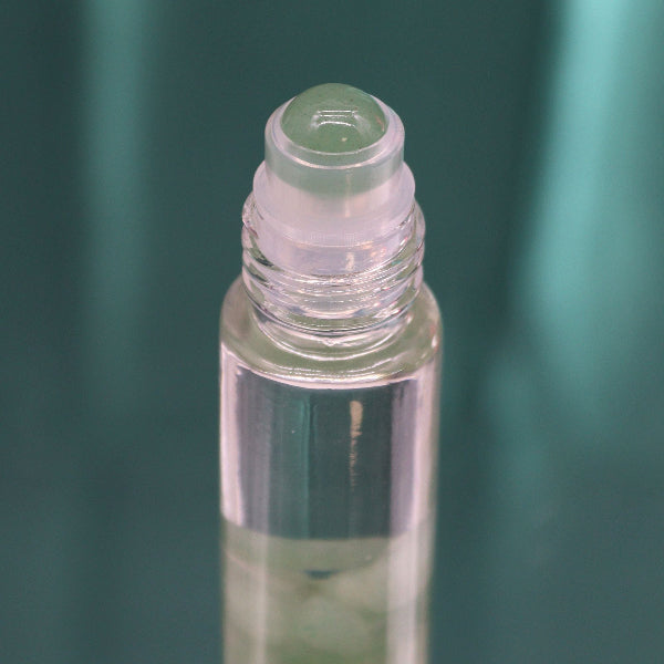 Clear glass roller bottle with green cap on a green background