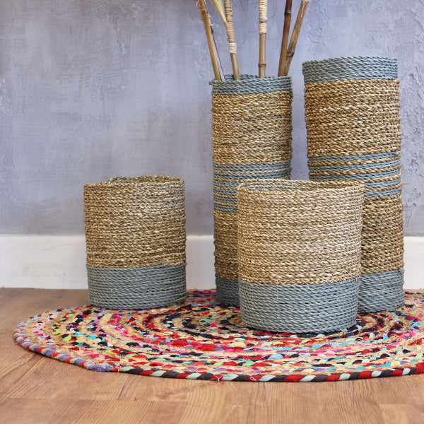 Set of woven cylindrical baskets with gray accents on a colorful rug.