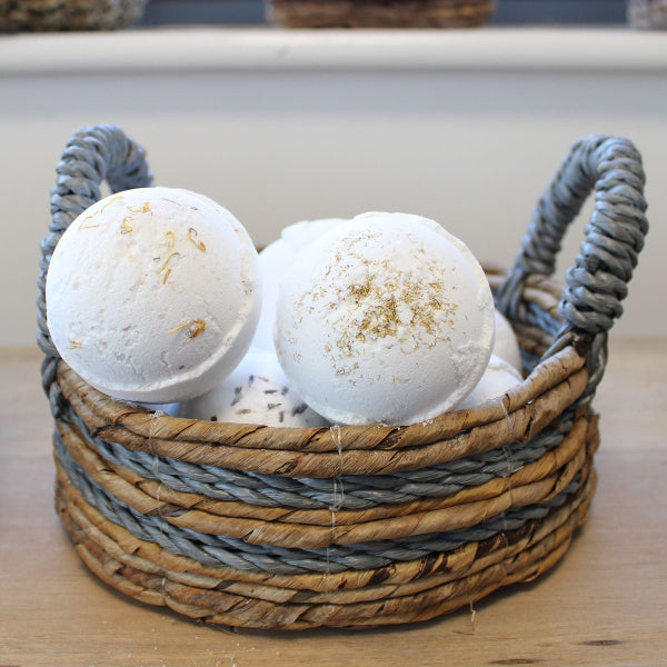 Bath bombs in a woven basket with a rope handle on a wooden surface.