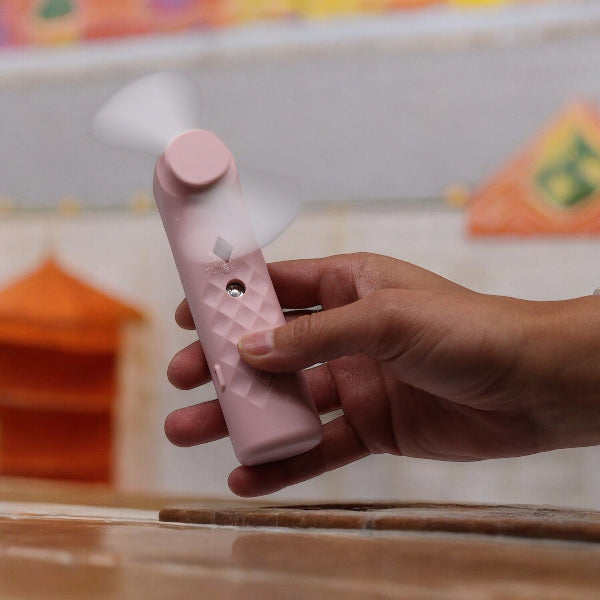 Hand holding a pink and white device with a blurred background