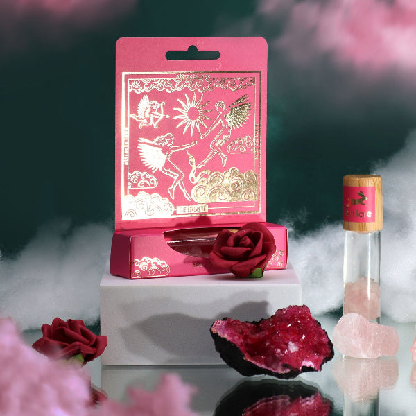 Pink decorative item with fairy design, red rose, and crystal on a dark background