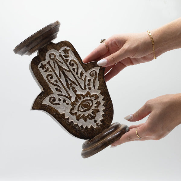 Hand holding a wooden stamp with intricate design on a white background