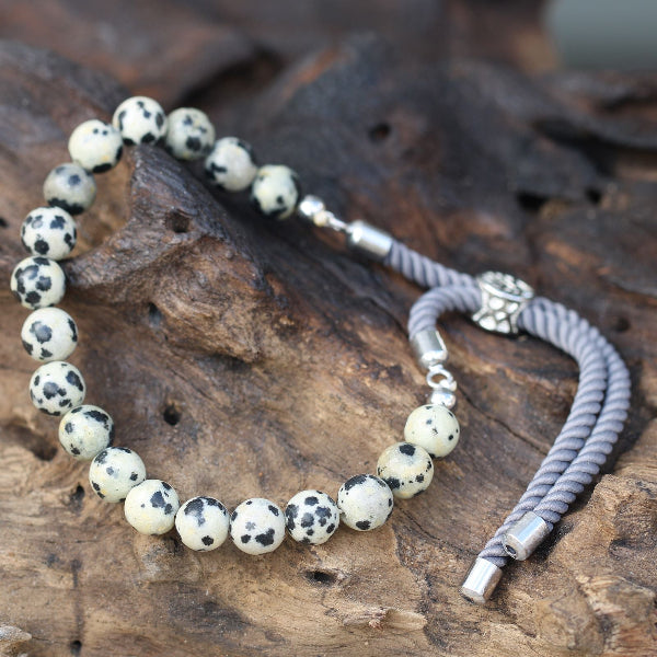 Necklace with dalmatian jasper beads and silver accents on a wooden surface
