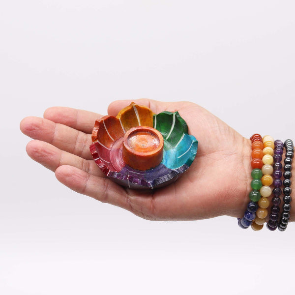 Hand holding a colorful chakra stone with a white background
