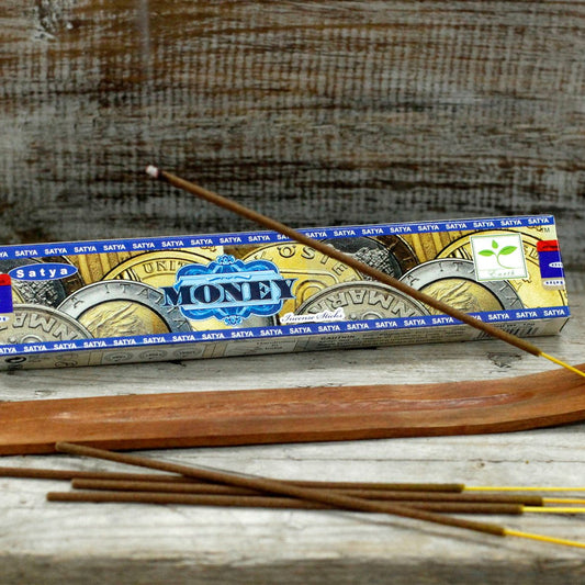 Incense sticks with Satya Money packaging on a wooden surface