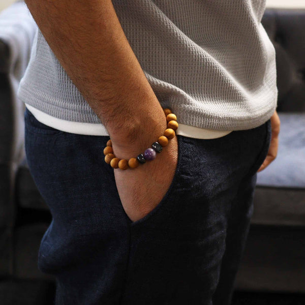 Person wearing a bracelet with beads, standing indoors.