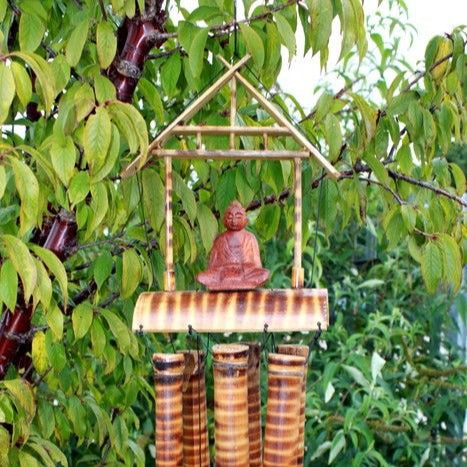Bamboo wind chime with Buddha figure hanging in a tree