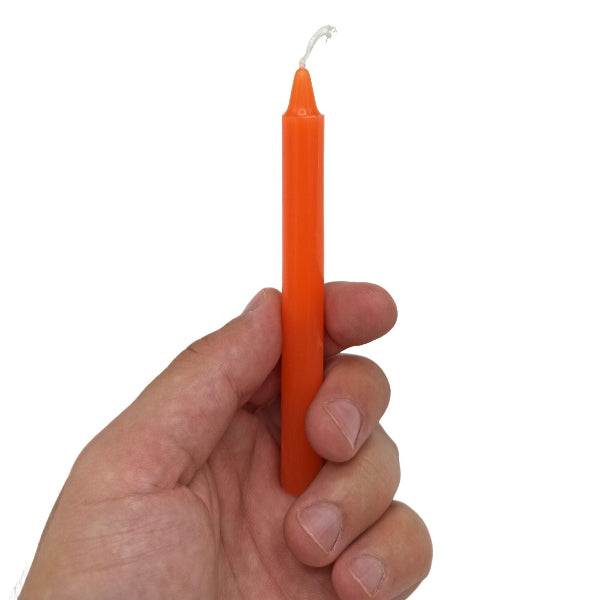 Hand holding an orange candle against a white background