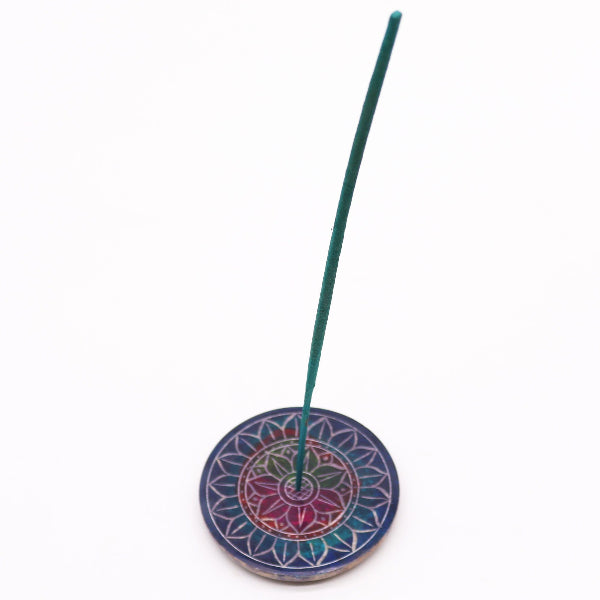 Incense stick on a colorful circular holder against a white background