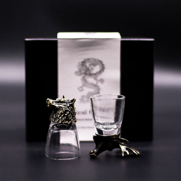 Two shot glasses with decorative bases on a dark background