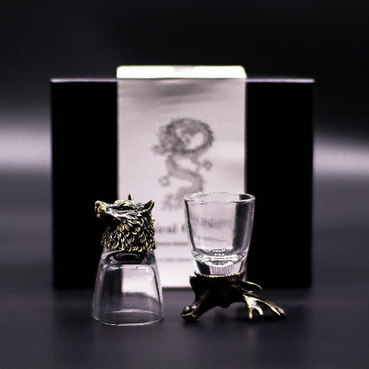 Two shot glasses with decorative bases on a dark background
