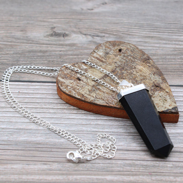 Black and silver pendant on a chain against a wooden background