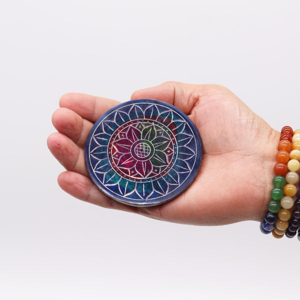 Hand holding a colorful mandala coaster with a white background