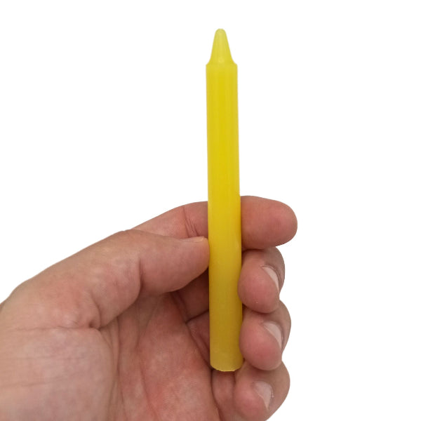 Hand holding a yellow candle against a white background