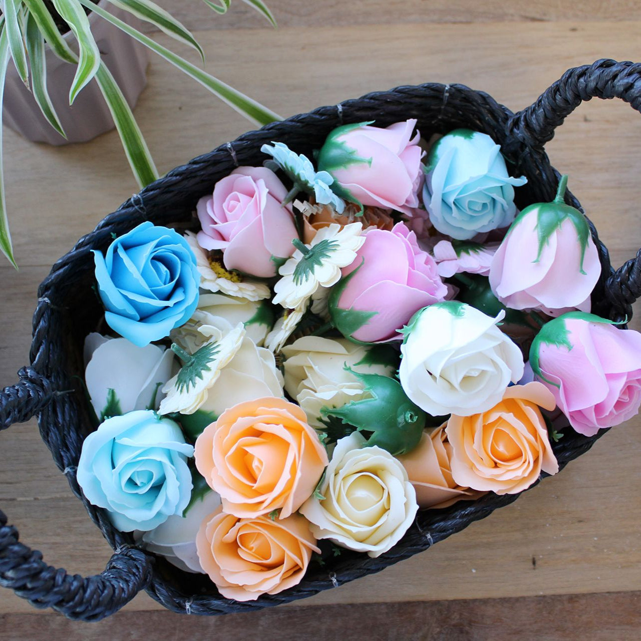 Basket filled with colorful artificial flowers on a wooden surface