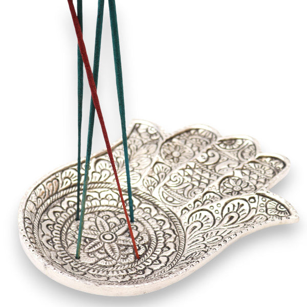 Decorative leaf-shaped incense holder with incense sticks on a white background