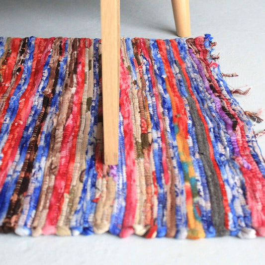 Colorful fabric with tassels on a wooden stick against a light background