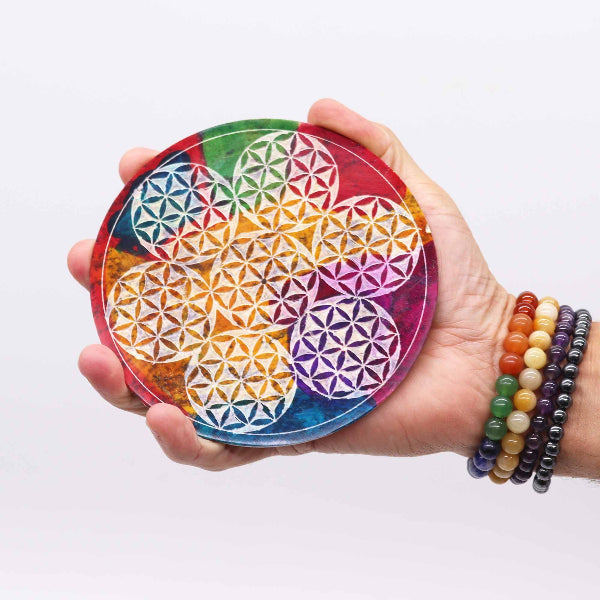Hand holding a colorful geometric coaster with a white background