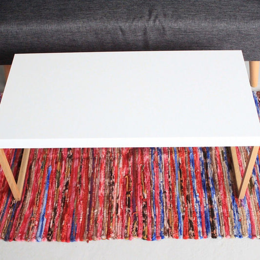 Colorful striped rug with a white table and gray chair on a light gray floor.