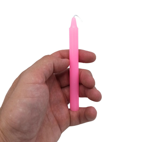 Hand holding a pink candle against a white background
