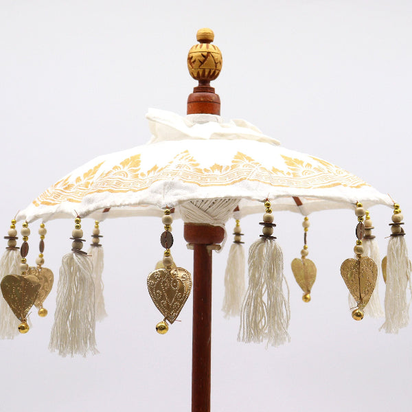 Decorative umbrella with gold accents and tassels on a white background