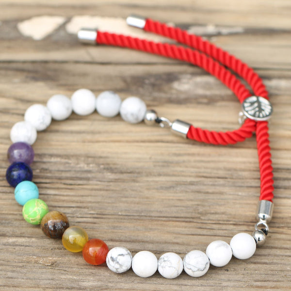 Necklace with multicolored beads and red cord on a wooden surface