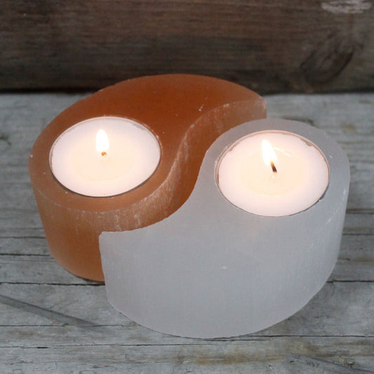 Two candle holders, selenite with candles inside on a wooden surface.