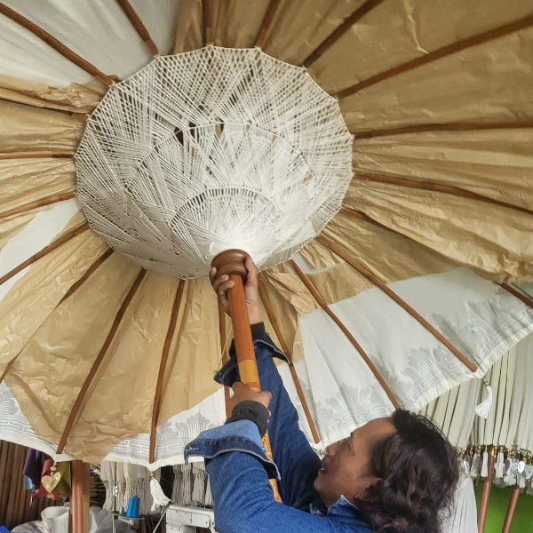 Person holding a large decorative umbrella indoors with various items in the background