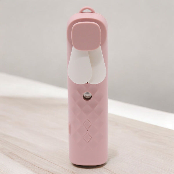 Pink handheld device with a white nozzle on a light wooden surface.