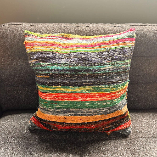 Multicolored striped pillow on a gray sofa
