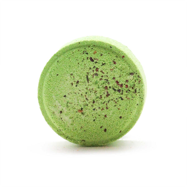 Green bath bomb with speckles on a white background