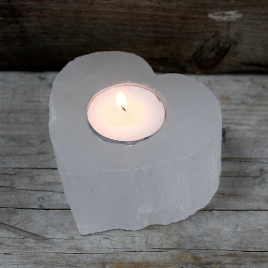 Heart-shaped stone candle holder with a lit candle on a wooden surface