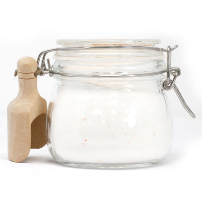 Clear glass jar with wooden scoop on a white background