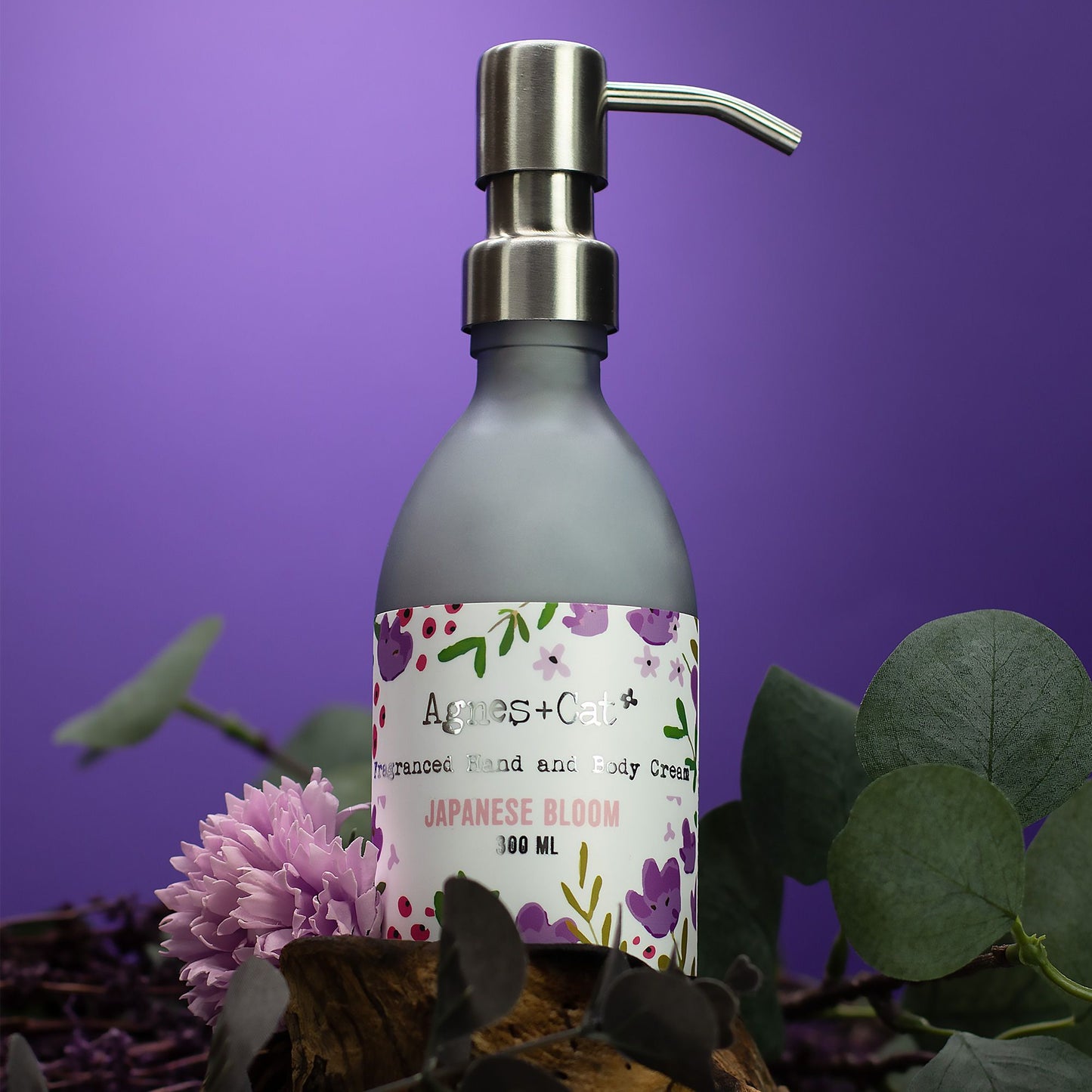 Gray bottle with a pump dispenser on a purple background with flowers and leaves.